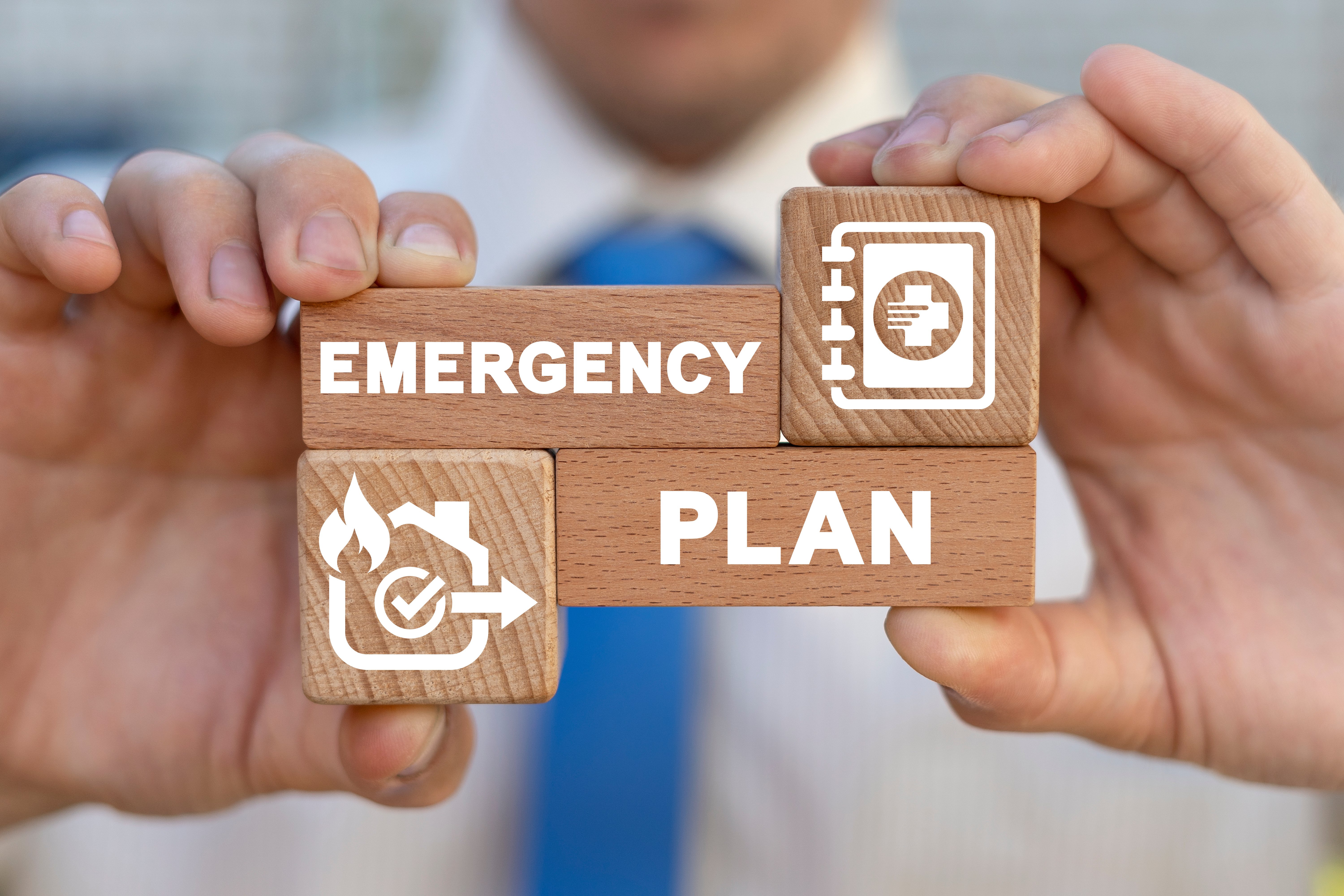 a person holding woodenblocks that say Emergency Plan